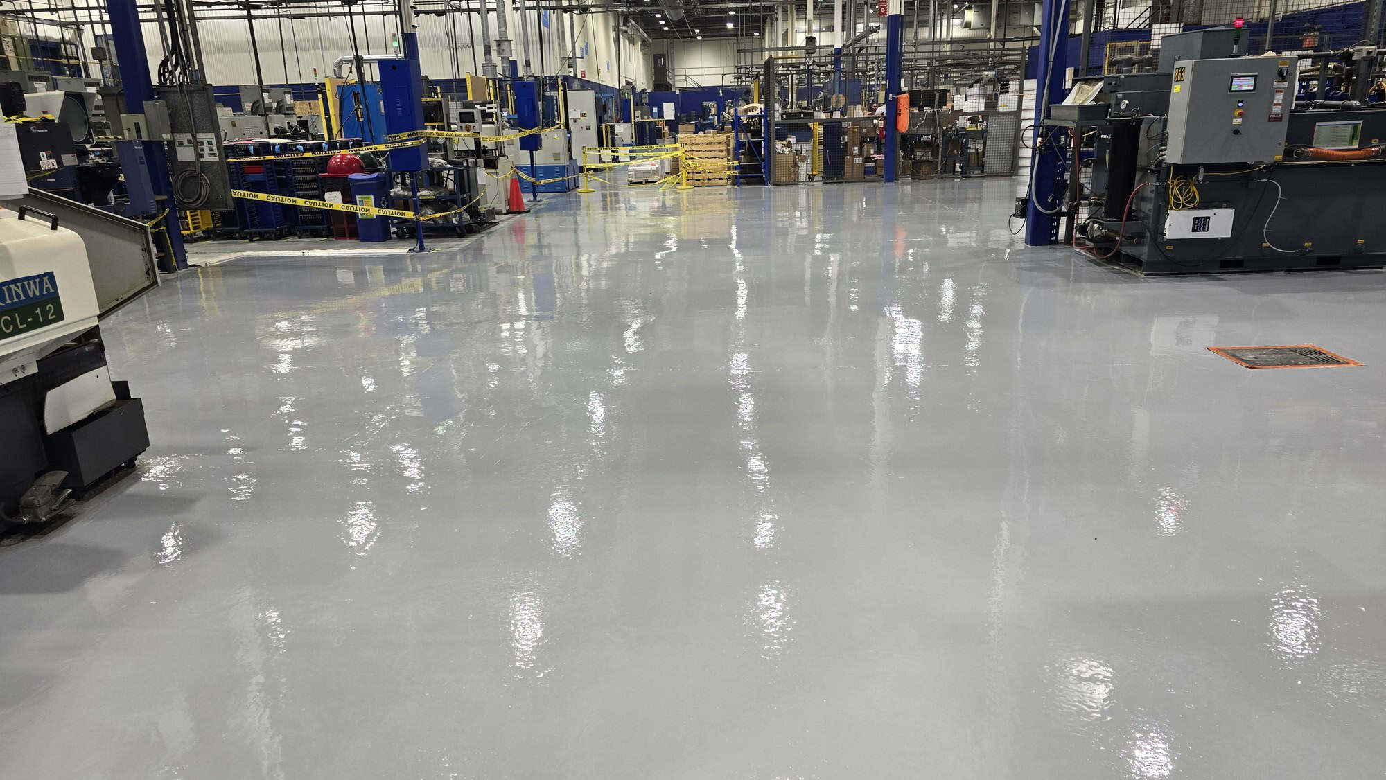 Second epoxy coat rolled across an industrial warehouse concrete slab near Montreal