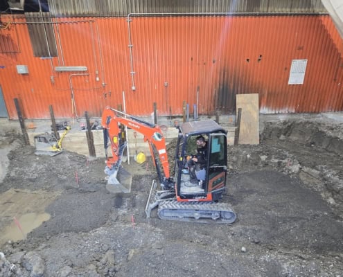 Mini-excavator excavating subgrade for industrial concrete work in Montreal
